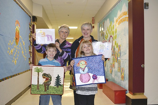Greywolf students Colby Watters and Brynless Dearinger show off their new quilts that Ilise Osier and Lydia Nelson made reinterpreting their artwork for the Sunbonnet Sue Quilt Club's annual show in July. The quilters gave the art back to the young artists on Nov. 5 as a thank you.