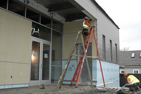 Construction staff install metal siding used for the exterior of the city’s new civic center.