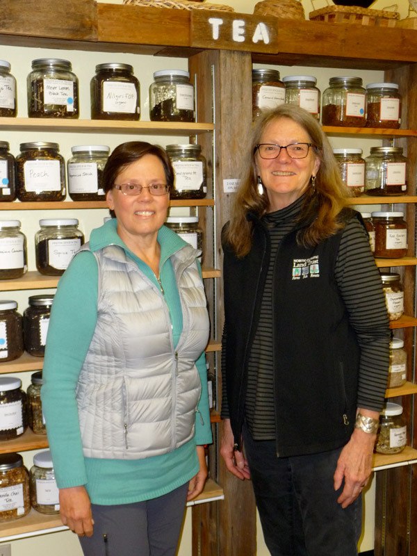 Local Dollars & Sense members Sarah Miller and Karen Westwood stand by a large assortment of teas at Sequim Spice and Tea at 139 W. Washington St. A low-interest loan from their club helped the owners move to a larger space so the business could add a tea room.