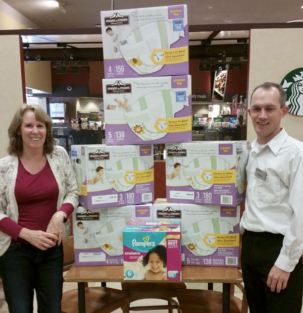 My Choices’ center manager Lori Pritchard stands with Sequim Safeway representative Isaac Peiffer in front of the diapers donated by Safeway to My Choices.