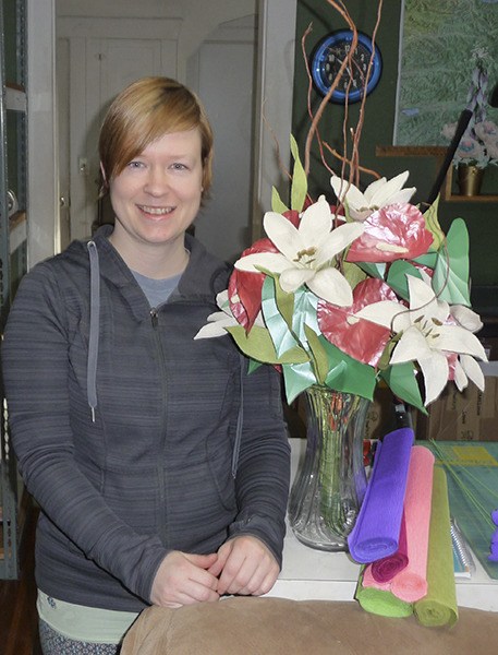 Janita Court poses with an impressive paper bouquet of red anthurium and white lilies she crafted by hand.