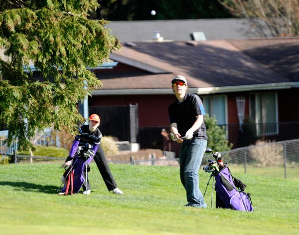 Sequim freshman Joey Oliver watches junior Jake Sparks take a shot toward the green in a home opening match on March 16.