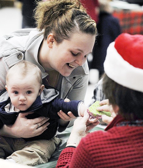 Six-month-old Bentley Berry gets a paint handprint at the First Teacher Santa’s Breakfast in 2013. Helping out is Kayla Heckthorn.