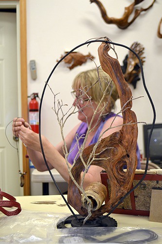 Coleen Dennis finishes up a driftwood necklace prior to the Olympic Driftwood Sculptors sixth annual lavender show. She said making driftwood art is like an opening a present because you don’t know what’s underneath the bark.