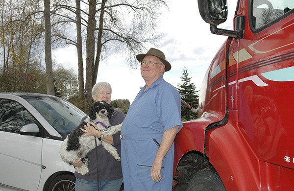 Carrie Blake Park’s newest hosts Merrily and Budd Nash and their dog Katie stand between their small Smart car and their huge-semi truck they use to travel the countryside.