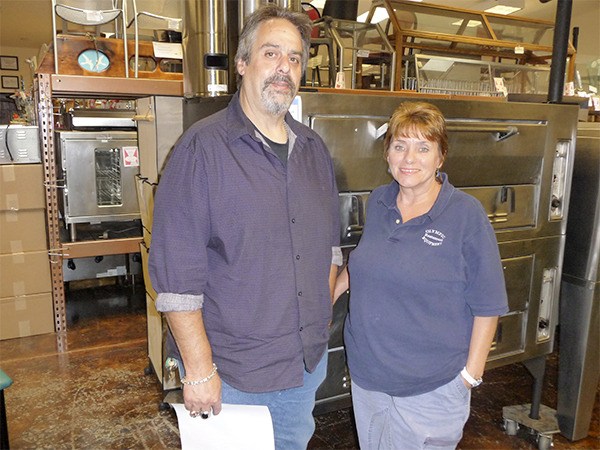 Olympic Restaurant Equipment and Supplies owner Eric Schwartz and his business manager Judi Jones pose in front of a large commercial oven.