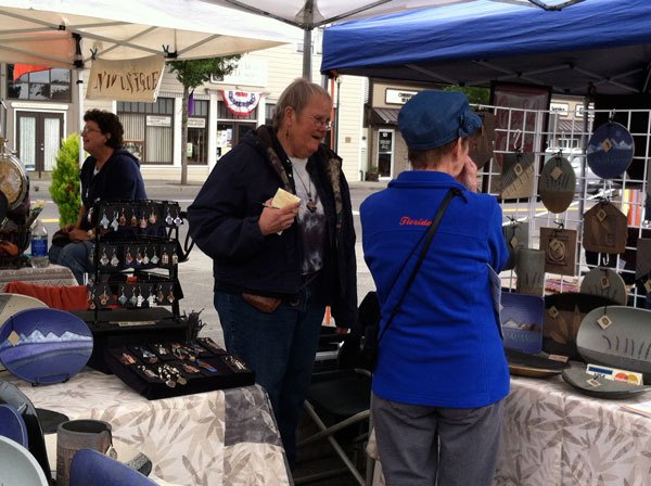 Michel McCarter of Madrona Ridge Pottery talks with a customer at the Sequim Farmers Market.