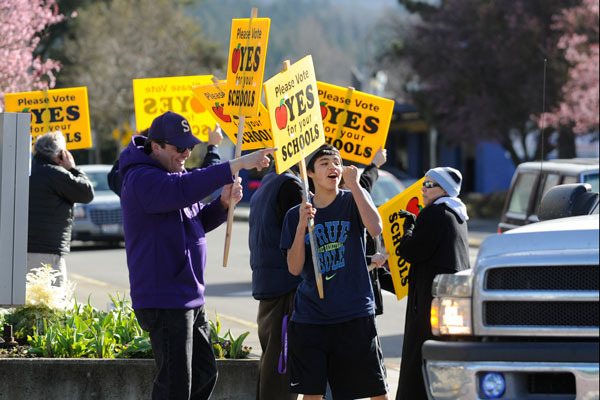 Shawn Langston and son Rigo Langston join a crowd of school bond supporters in downtown Sequim on March 19.