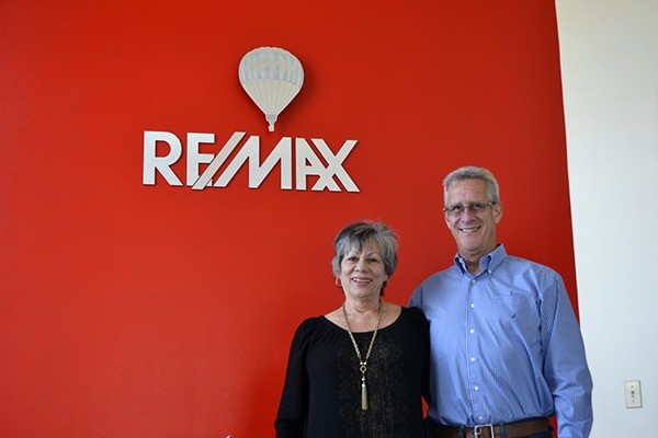 Liz and Richard Parks stand at the entrance of the recently renamed and moved RE/MAX Prime