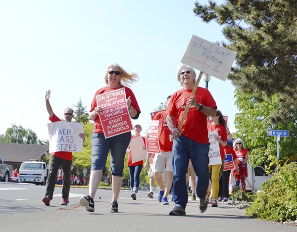 Sequim Middle School teachers Allison Hastings and Steve Koehler walk from the Sequim Avenue bypass with a group of teachers on May 18 during Sequim School District’s walkout to protest the Legislature’s failure to fully fund public schools