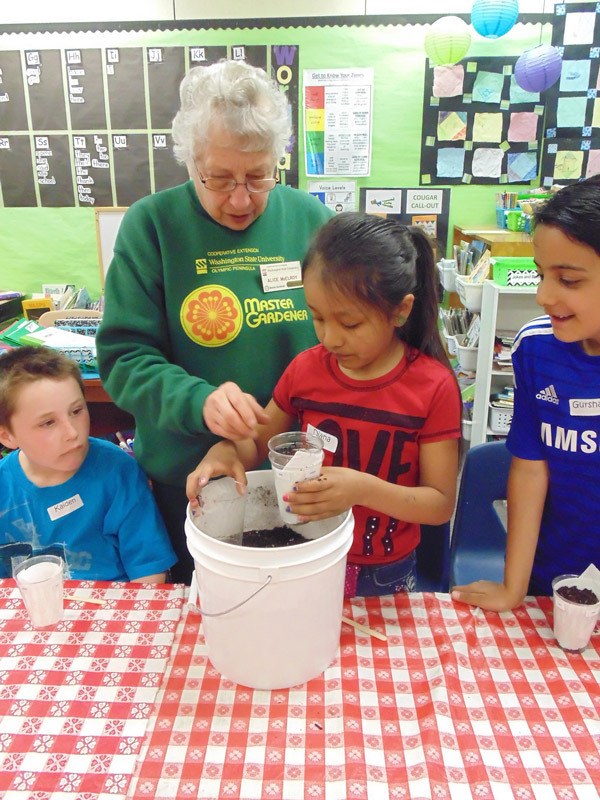 Master Gardeners volunteer Alice McElroy assists Haller second-graders Kaiden Tosland