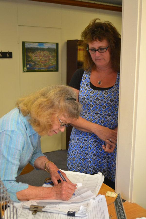 Susan Shotthafer signs two petitions before handing them to Karen Kuznek-Reese