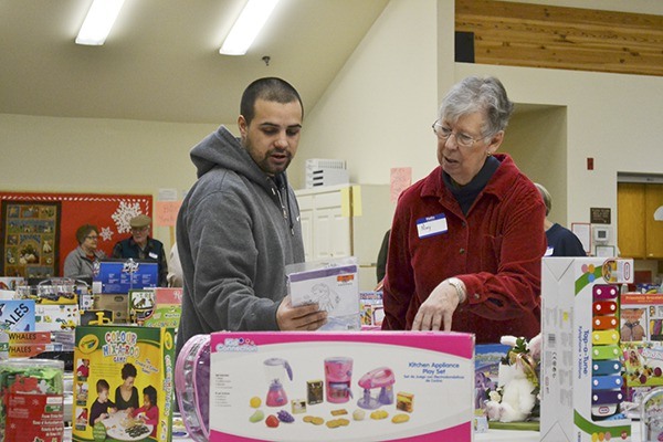 Ramon Lopez looks for the right toys for his 4-year-old daughter with help from Mary Evert at the 67th Toys for Sequim Kids event.