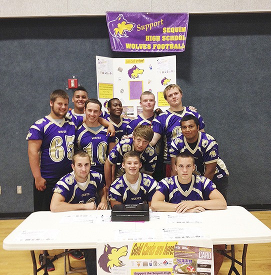 Sequim High School football players pre-sell gold cards at the Sequim Sunrise Rotary Club’s salmon bake on Aug. 10. Back row