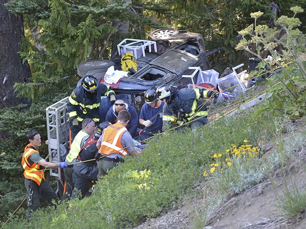 Firefighter/paramedics from Clallam 2 Fire-Rescue (Port Angeles) help rescue the driver and two passengers in a vehicle that left Hurricane Ridge Road and rolled on June 26.