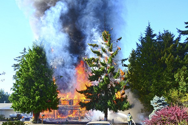 Firefighters respond to a two-story fire west of Port Angeles on July 30.