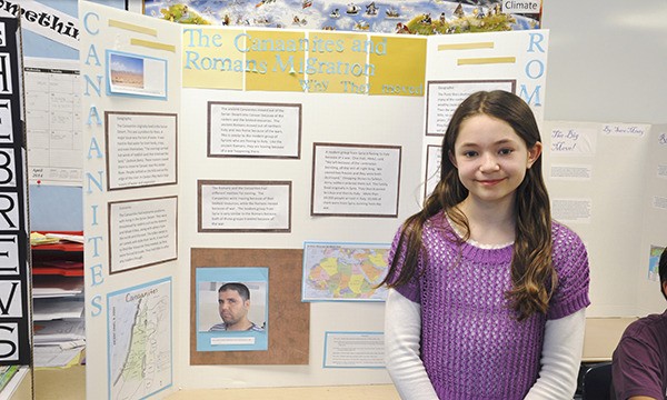 Sixth-grader Kianna Miller from Paul Pinza’s class stands with her history display board on migration of the Canaanites and Romans.