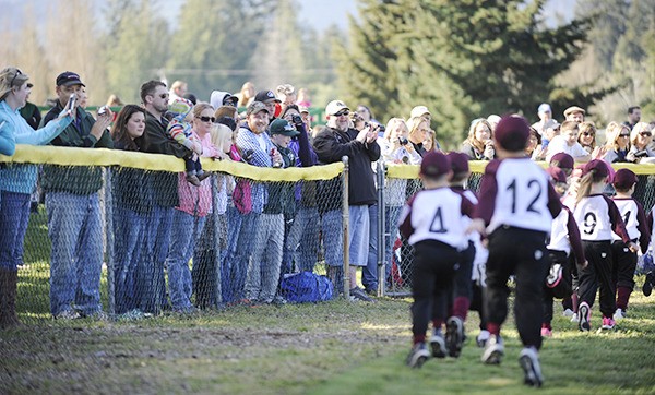 Parents cheer on their Little League players as teams are introduced at the league’s Opening Day on April 12.