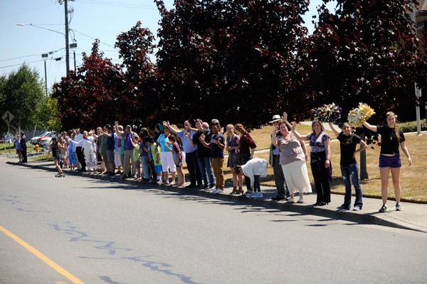 A group of Sequim residents gather in front of the Sequim Church of Jesus Christ of Latter-day Saints on July 21 to wave and honor former Sequim schools’ traffic attendant Mike Lovejoy (bottom left inset) at his funeral. Lovejoy was well-known in his tenure for waving at each vehicle that drove by.