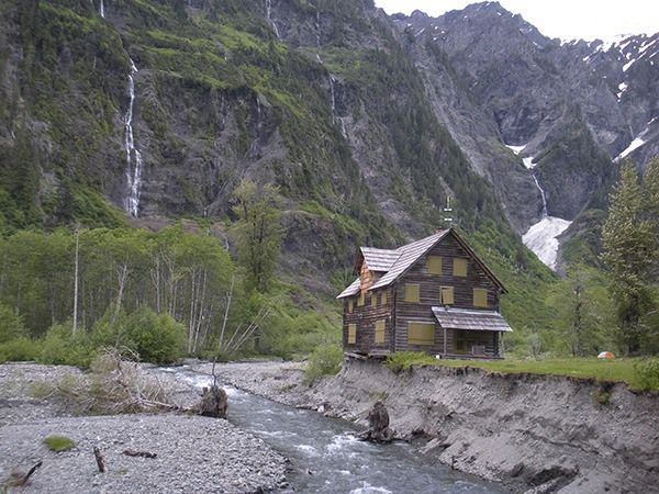 Olympic National Park’s Enchanted Valley Chalet is expected to be temporarily moved in September. Recent photos show the shifting East Fork Quinault River is undercutting the chalet by about eight feet.