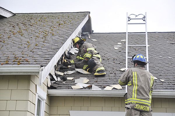 Fire District 3 firefighters examine a roof at a home on Craftsman Court near Bell Hill that was damaged by lightning.
