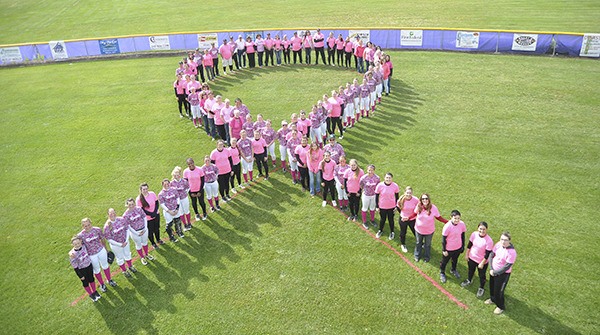 Sequim and Port Angeles High School softball players join community members in forming a ribbon on the field just before the Wolves-Roughriders April 29 Olympic League game in Sequim. The teams held their second “Pink Up!” event to raise awareness of and funds for battling cancer.