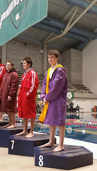 Mathew Craig accepts his eighth-place medal on the podium after a strong finish at the Washington state 2A swimming and diving championships last weekend.