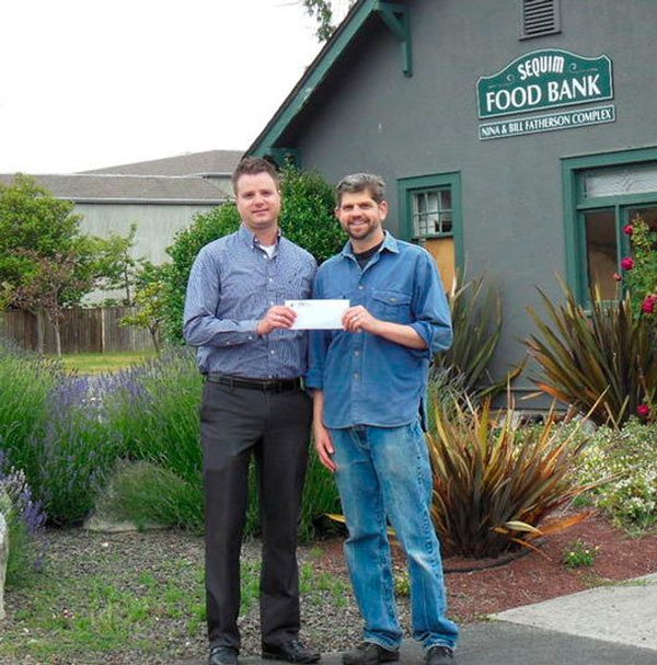 Marcus Oden hands a check to Mark Ozias of the Sequim Food Bank from donations he received for running a marathon.
