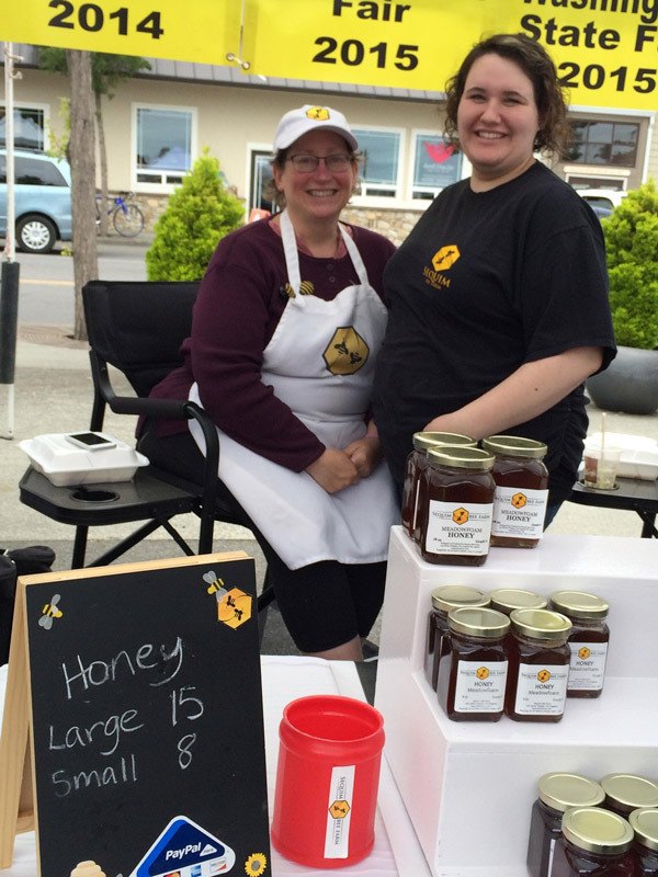 Meg Depew and daughter/assistant Darcy VanWinkle bring smiles — and plenty of local honey — to the Sequim Farmers Market.