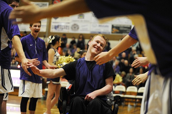 Player Isaiah Spalding gets high-fives from Sequim High varsity boys basketball players prior to the first Sequim Wolves Unified Basketball Game on Jan. 13.