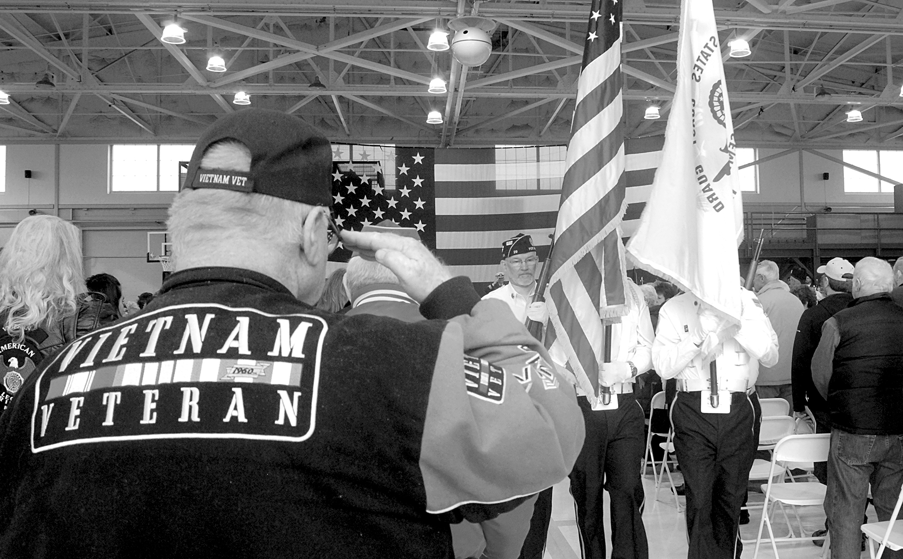 Mike Money of Port Angeles, a U.S. Navy veteran who served in Vietnam, salutes as a color guard passes during last Friday’s Veterans Day ceremony in the hangar of U.S. Coast Guard Air Station/Sector Field Office Port Port Angeles. (Keith Thorpe/Peninsula Daily News)