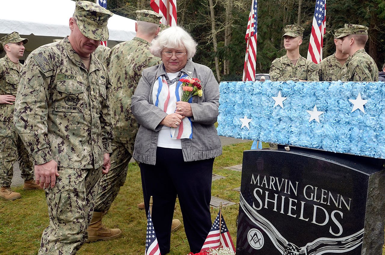 Joan Shields, the widow of Medal of Honor recipient Marvin Shields, stands beside his grave with a group of local servicemen who came out on Veterans Day to honor her late husband’s service Friday. (Cydney McFarland/Peninsula Daily News)