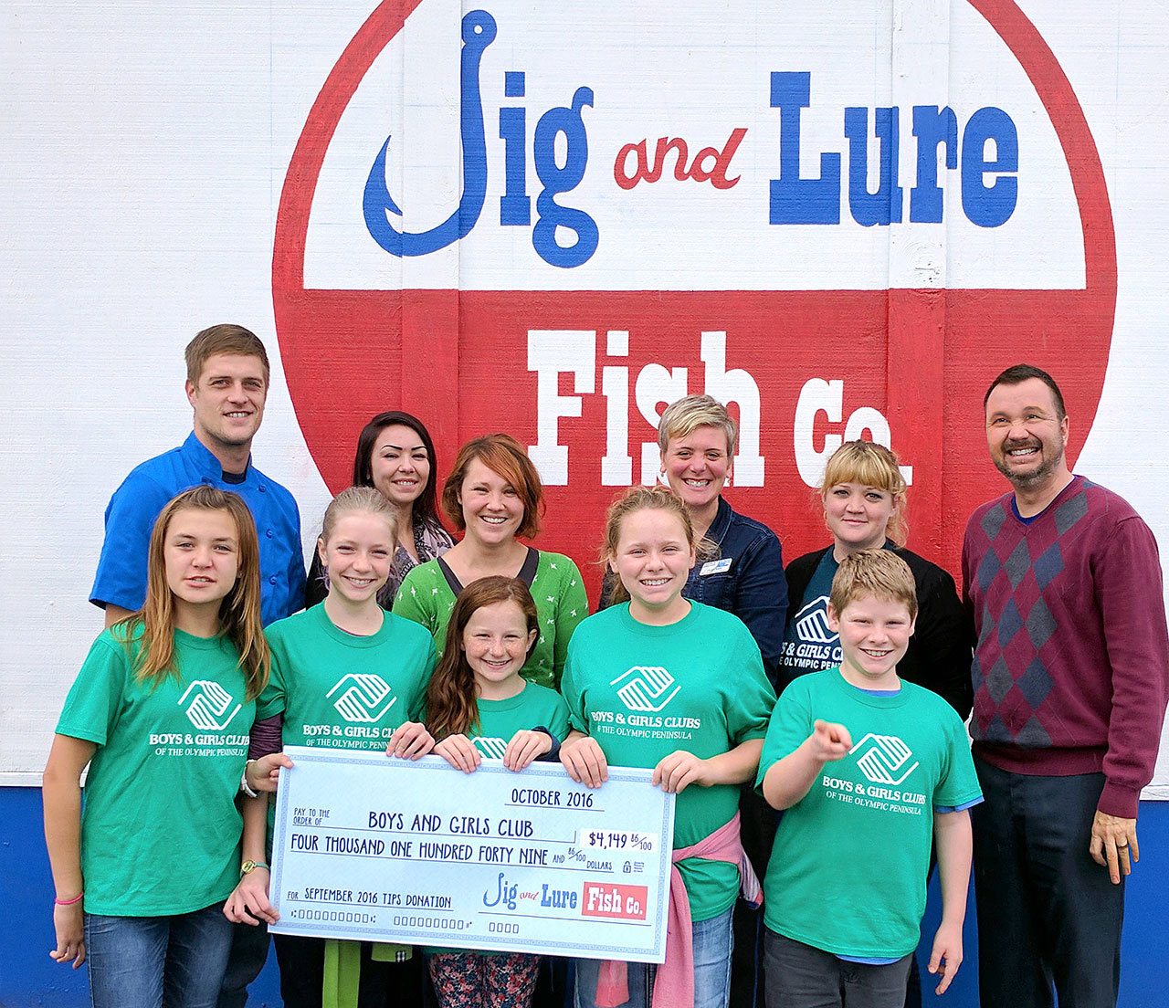 Port Angeles Boys and Girls Club members accept a check for $4,149.86 from the Jig and Lure Fish Company staff, accompanied by United Way and Boys & Girls Club staff. From back left are executive chef Brian Lippert, server Shawna Cochrum, guest services manager Christina Fenner, United Way resource development manager Christy Smith, Boys & Girls Club Port Angeles unit director Ashley Woolsey, and co-owner Stephen Fofanoff. Submitted photo