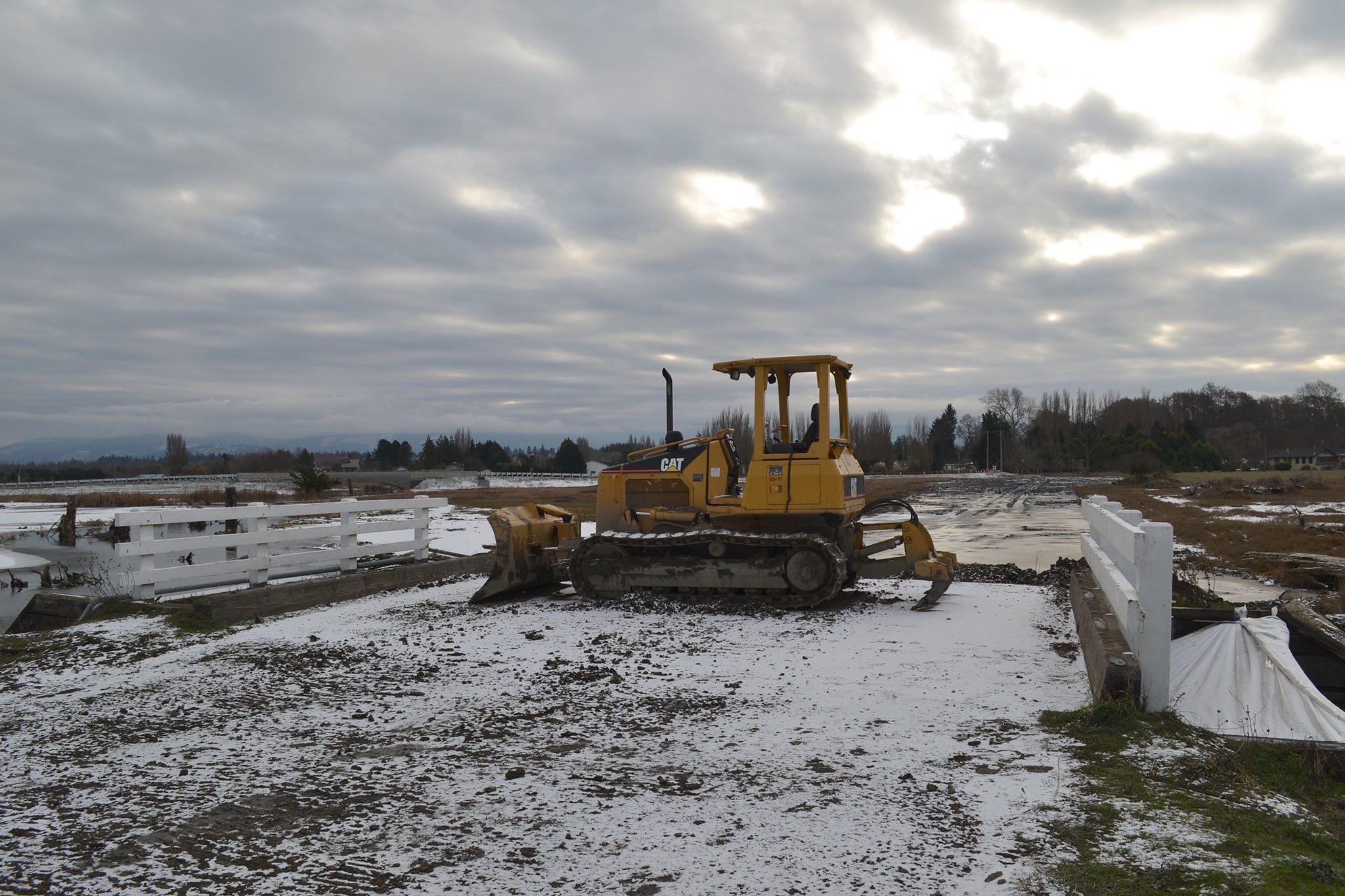 A bulldozer sits where the former Meadowbrook Creek bridge connected 3 Crabs Road and Sequim-Dungeness Way. Crews took the bridge out in December for a new bridge that allows the creek to make for better passage as migrating salmon stop into the estuary. Sequim Gazette photo by Matthew Nash