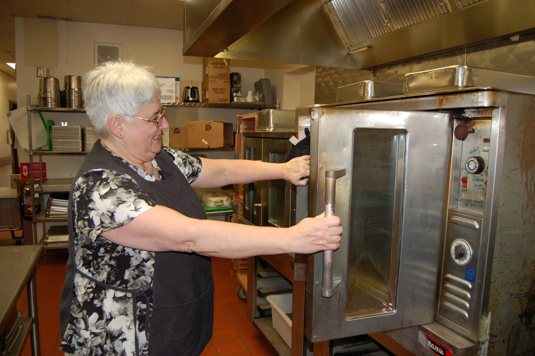 Laurie Campen, director of food services at the Sequim School District kitchen, opens an oven from the 1970s with only one door that opens. Sequim Gazette photo by Erin Hawkins