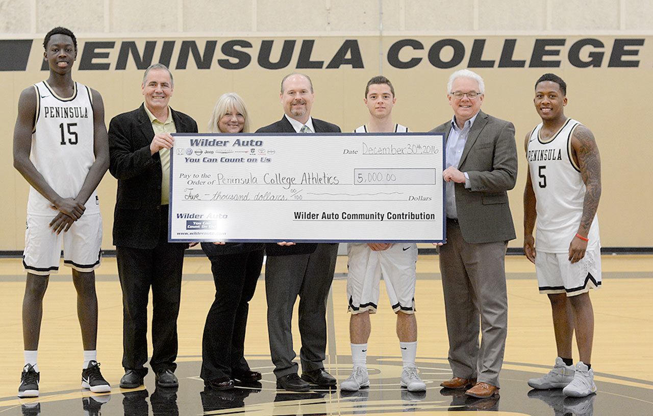 Representatives from Peninsula College accept a check for $5,000 from Wilder Auto on Dec. 30 at the PC Gym. From left, are Omar Lo, athletic director Rick Ross, Tami Rose and Dan Wilder Jr. from Wilder Auto, Jalon McCullough, President Dr. Luke Robins and Darrion Daniels. Photo by Kari Desser