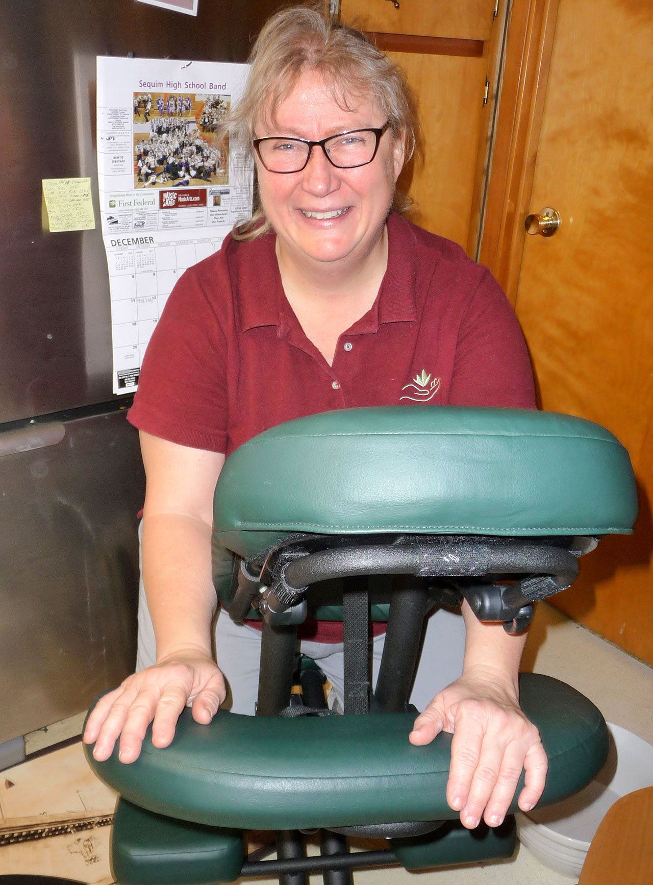 Massage therapist Cheryl Powell strikes a pose with her portable massage chair. Sequim Gazette photo by Patricia Morrison Coate