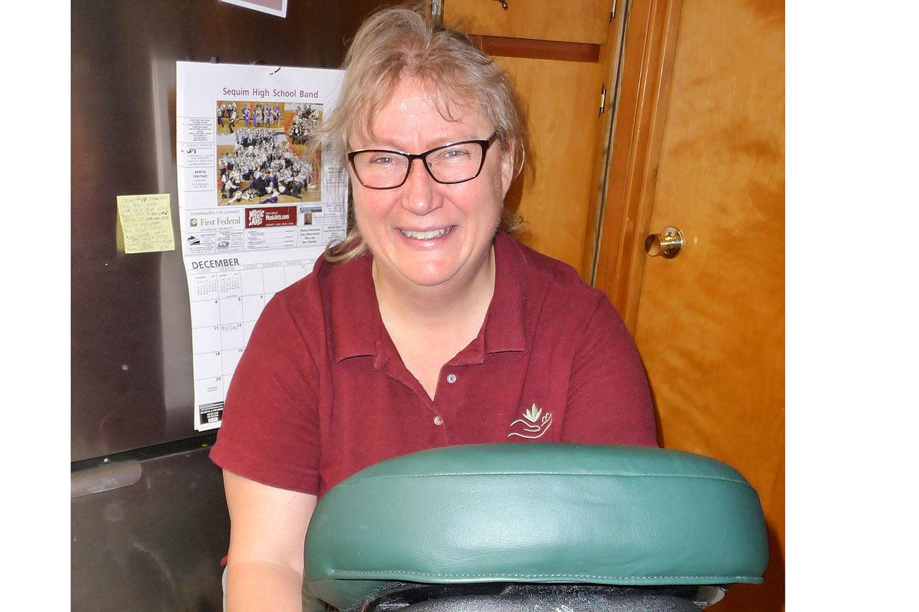 Massage therapist Cheryl Powell strikes a pose with her portable massage chair. Sequim Gazette photo by Patricia Morrison Coate