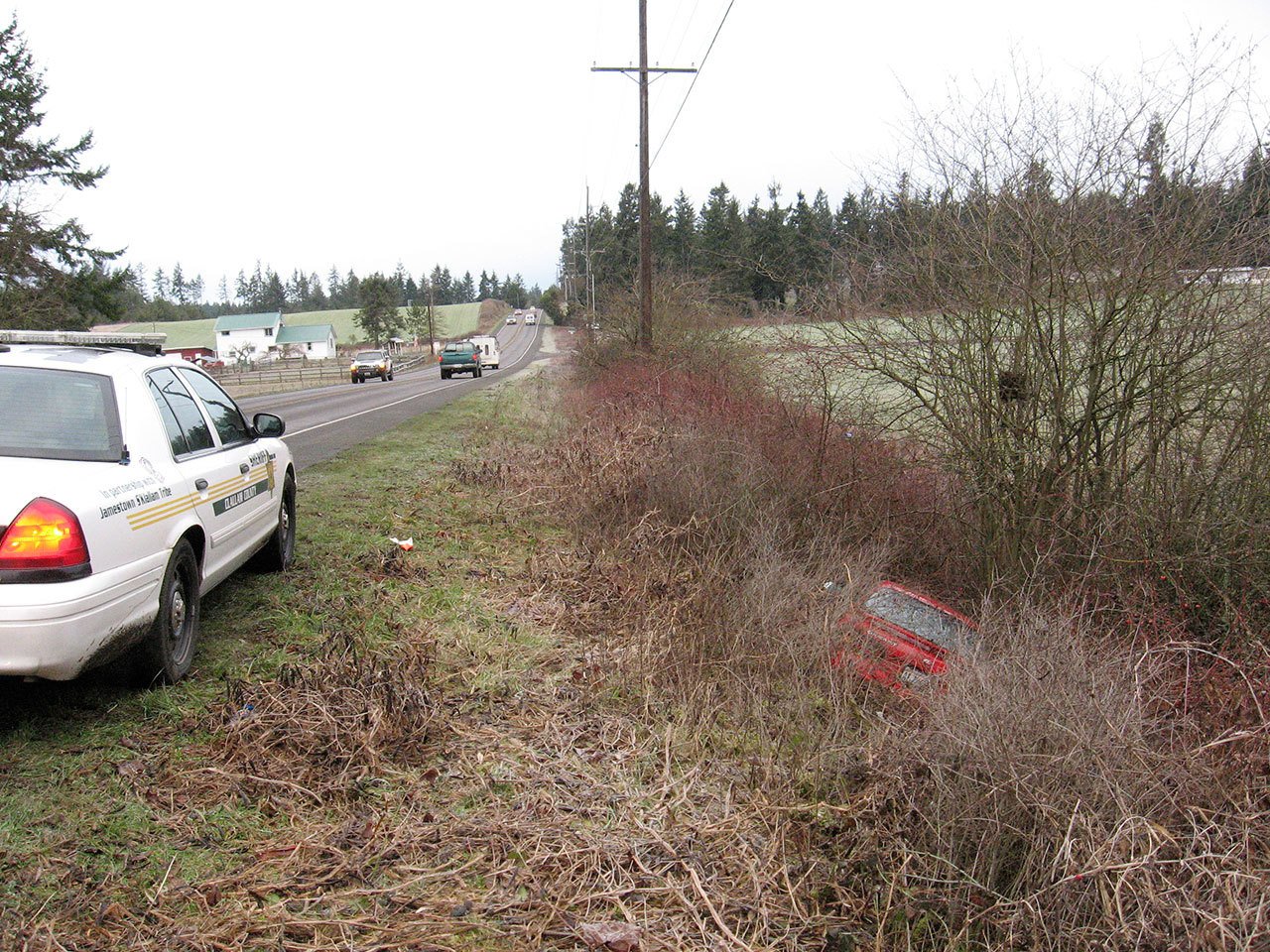 A Clallam County Sheriff’s Office cruiser sits along Sequim-Dungeness Way above a Toyota Celica found along the roadway. A man walking a dog found the Toyota and called 9-1-1, leading to the rescue of a Sequim resident parked inside. (Brandon Stoppani/Clallam County Sheriff’s Office)