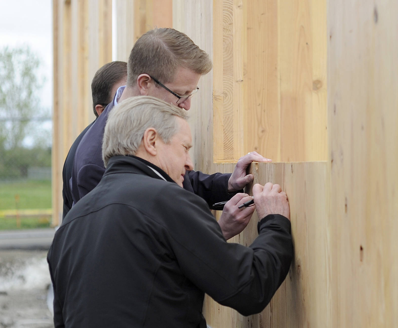 Washington State Rep. Steve Tharinger, foreground, and U.S. Rep. Derek Kilmer put their signature on a cross laminated timber modular building being built on the Greywolf campus. Sequim Gazette photo by Michael Dashiell
