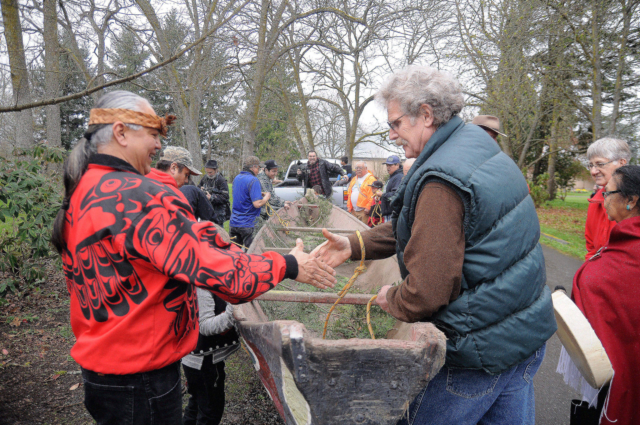 Vince Penn of the Quileute Tribe, left, and Frank Hanson, education and outreach coordinator at the University of Washington’s Olympic Natural Resources Center, shake hands as a hand-made canoe carved by William E. Penn is removed from Pioneer Memorial Park on April 8. Sequim Gazette photo by Michael Dashiell