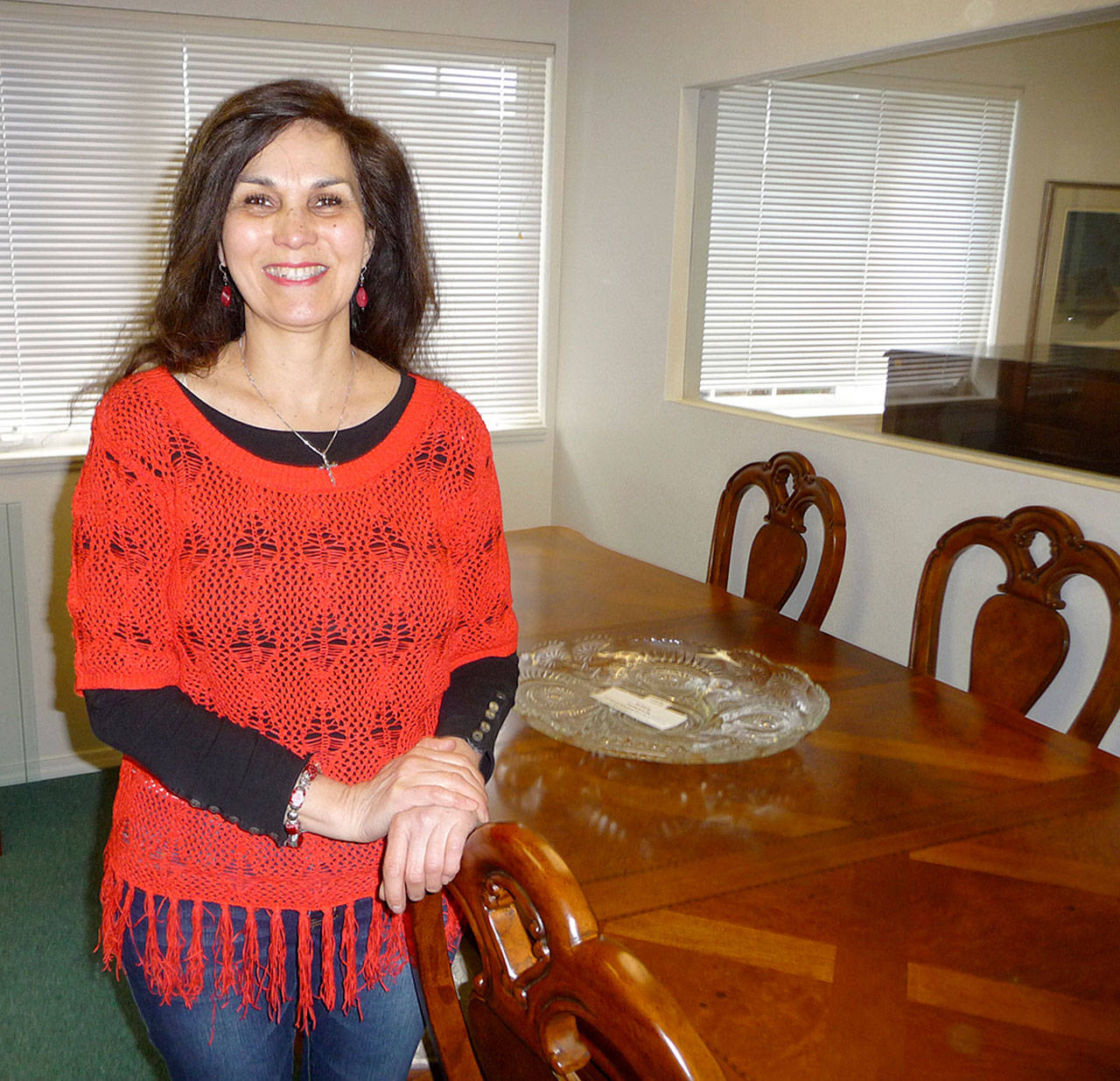Serenity House Thrift Shoppe manager Belle Muñoz poses with a grand dining room set by Thomasville, originally purchased for $7,000 and now for sale for $2,500 at Serenity Showcase. Sequim Gazette photo by Patricia Morrison Coate