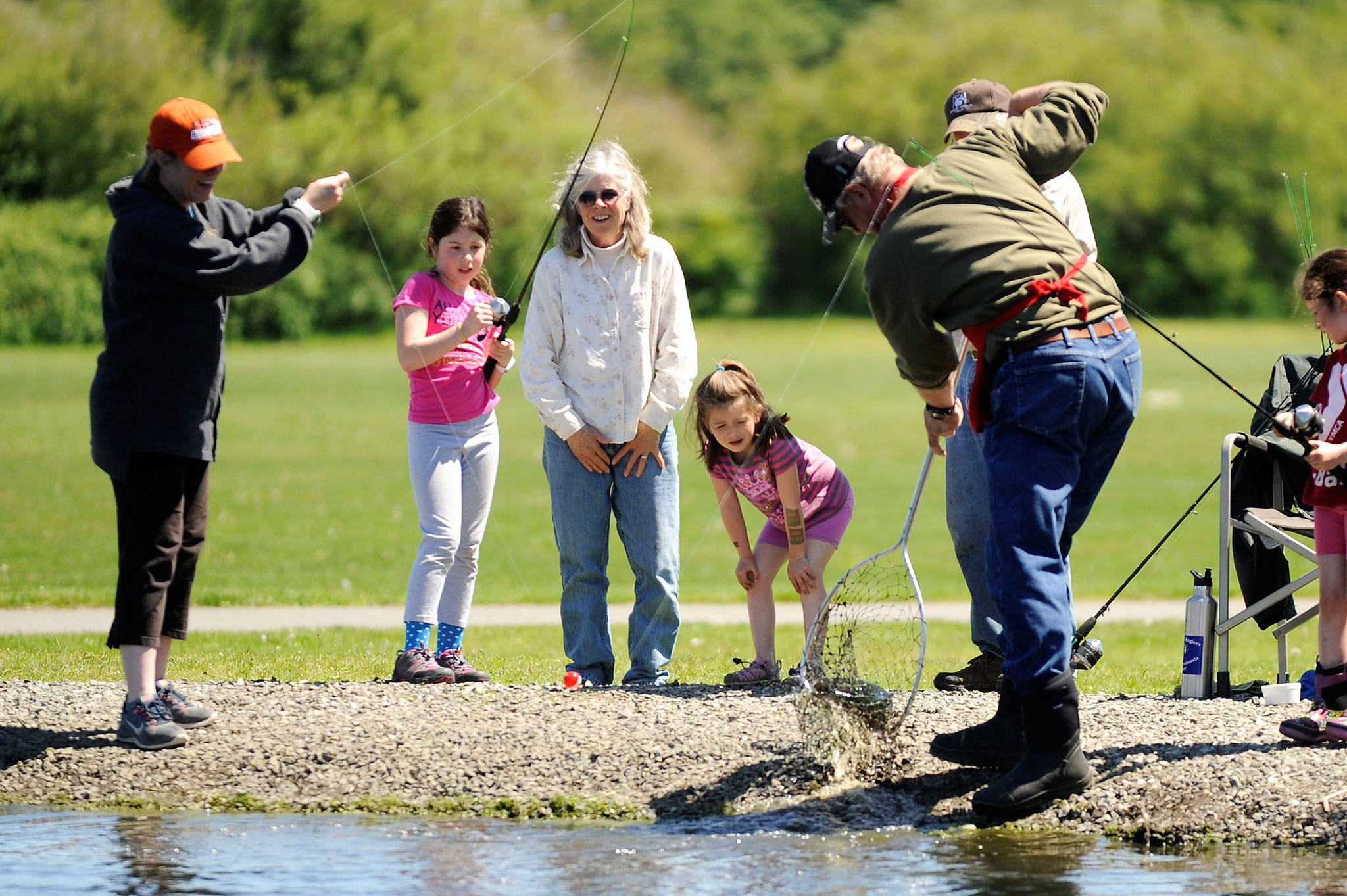 Sadie Miller, 8, of Port Angeles, brings in a fish with help from her mom Amy and Ron Hayes of the Puget Sound Anglers of the North Olympic Peninsula Chapter as her cousin Harper Hilliker, 5, and grandma Bonnie McCloskey watch in anticipation. Sadie and Harper were one of hundreds of children to participate at Kids’ Fishing Day on May 20 in the Water Reuse Demonstration Park pond north of Carrie Blake Park. Sequim Gazette photo by Matthew Nash