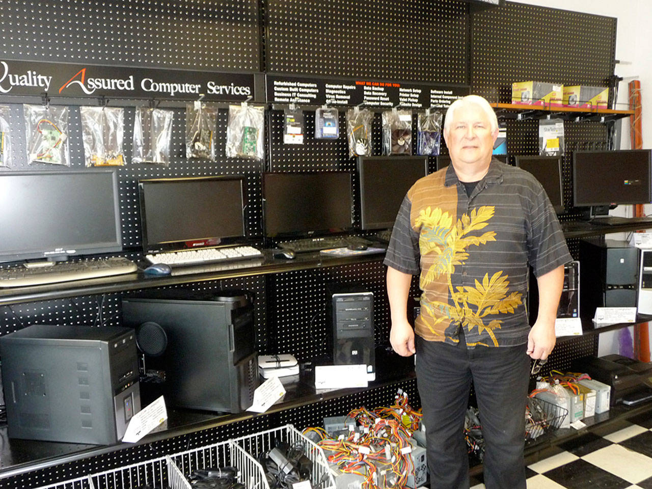 Jim Manderscheid, co-owner of Quality Assured Computer Services, displays a wall full of affordable refurbished computers. Sequim Gazette photo by Patricia Morrison Coate