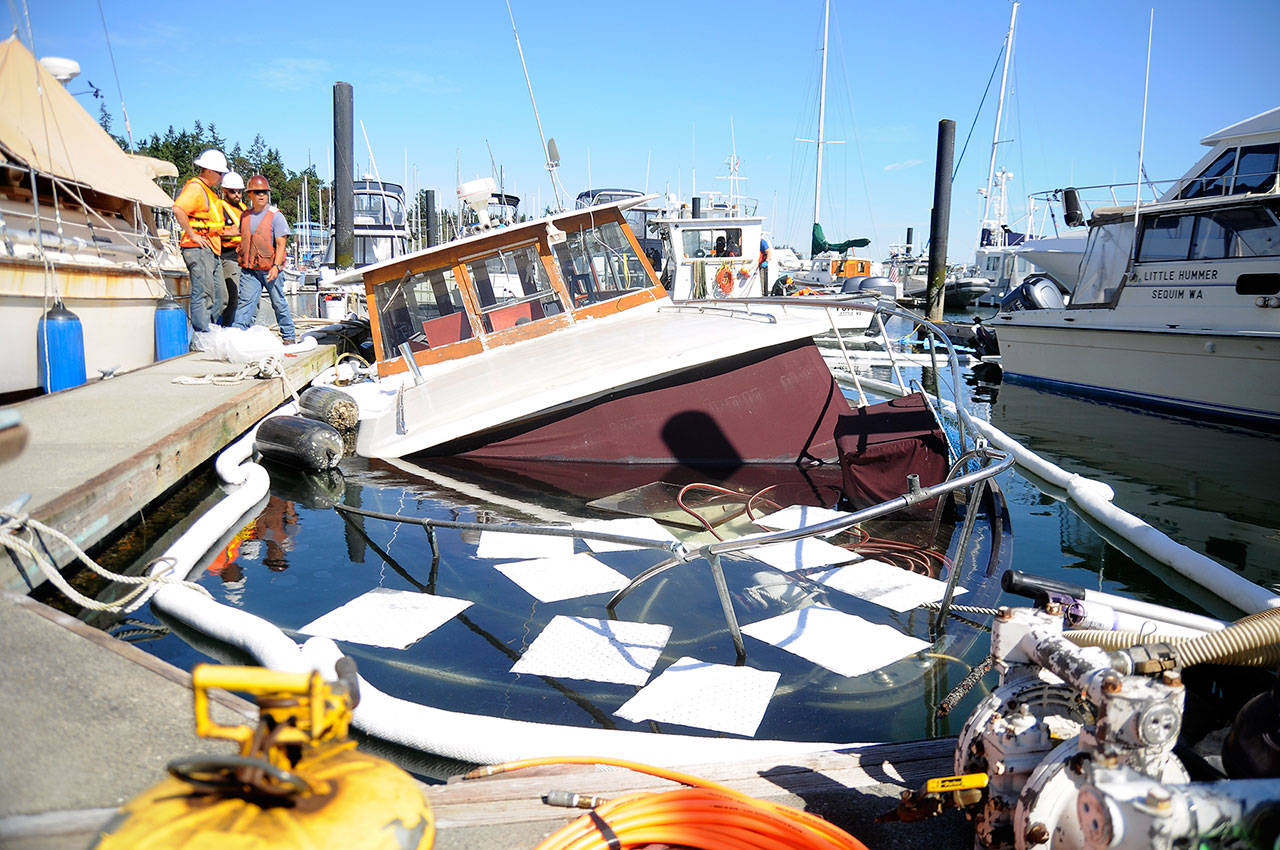 Personnel from Global Diving and Salvage work to secure leaking fuel from the Seattle-based Lady Mick, which began sinking July 18 at John Wayne Marina. Sequim Gazette photo by Michael Dashiell
