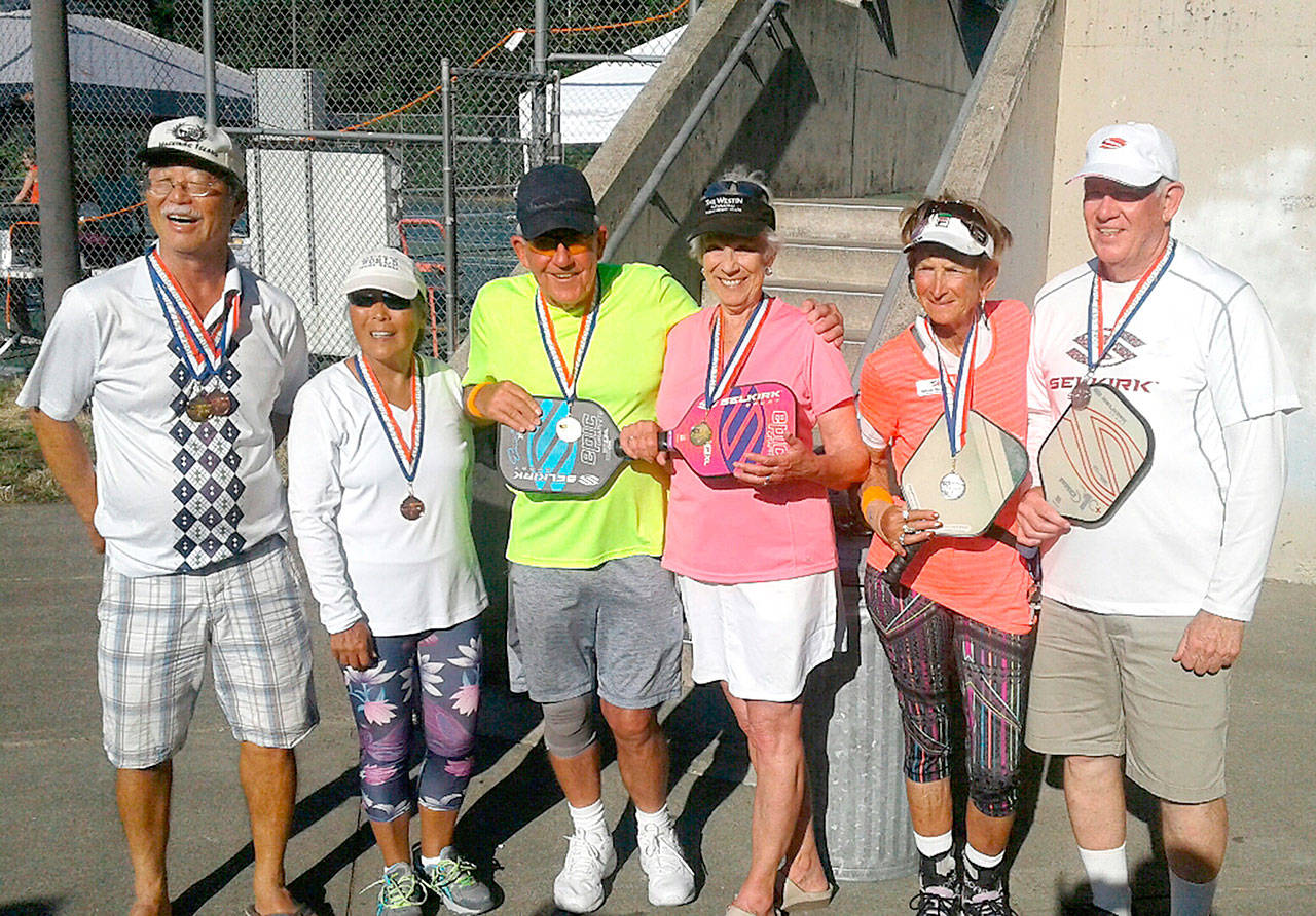 Bob Sester and Beverly Hoffman, both of Sequim, center, in yellow and pink, celebrate winning gold in the mixed doubles 70-plus division at the Senior Games in Auburn July 21-23.