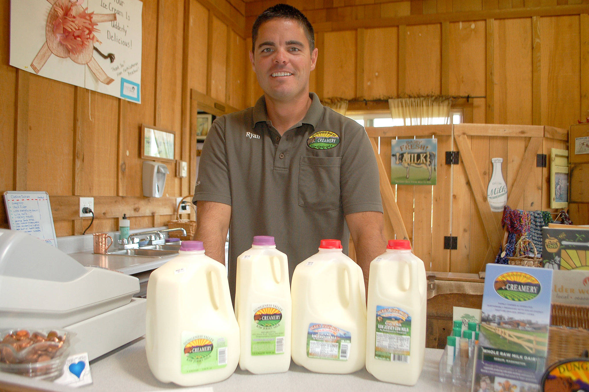 Ryan McCarthey, co-owner of Dungeness Valley Creamery, stands with cartons of Dungeness Valley Creamery whole raw milk and newly owned Jackie’s Jersey’s cartons after the companies merged Aug. 1. Sequim Gazette photo Erin Hawkins