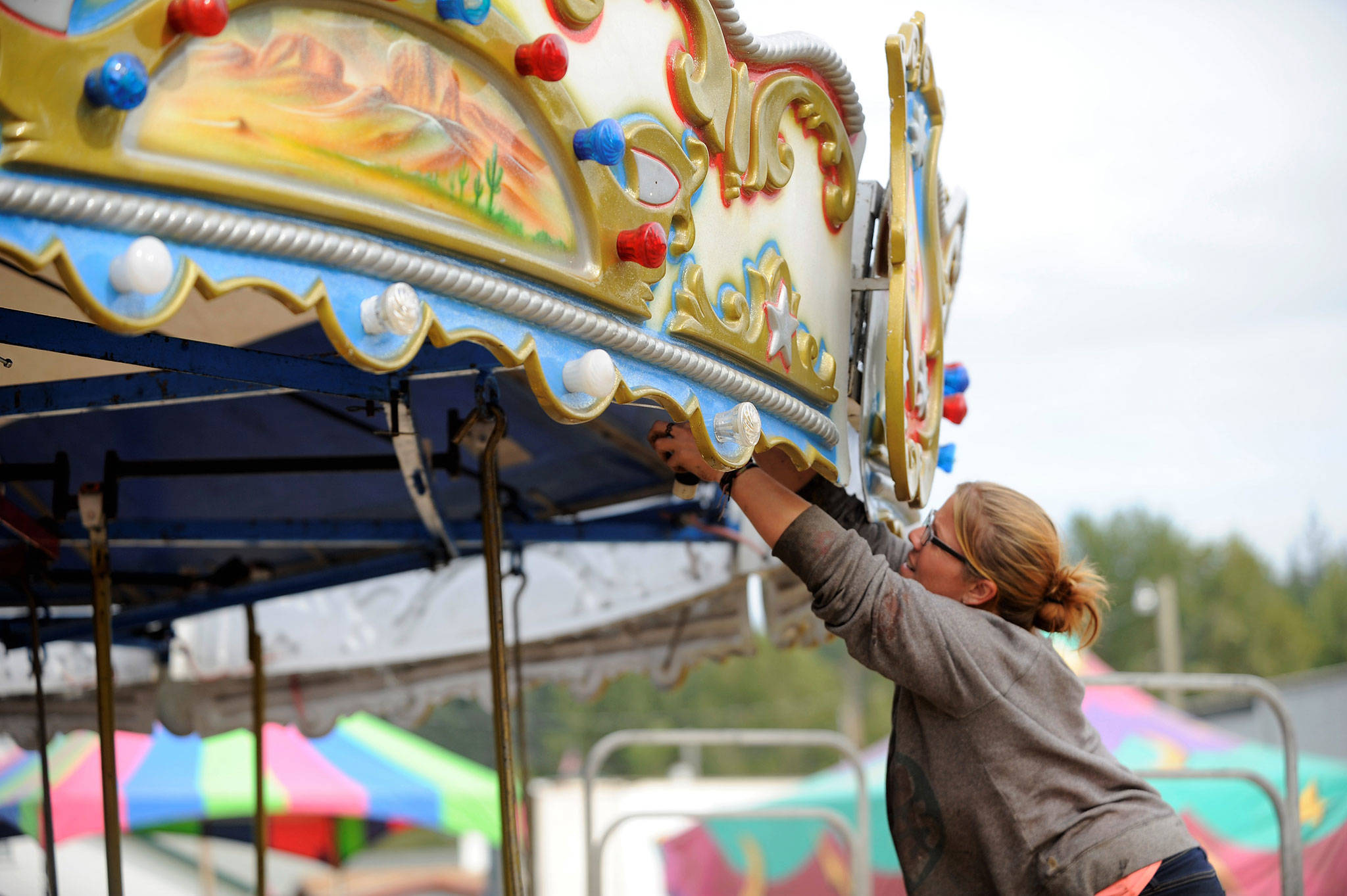 Amber Guy with Rainier Amusement of Portland, Ore., helps set up the merry-go-round at the Clallam County Fair on Aug. 14.