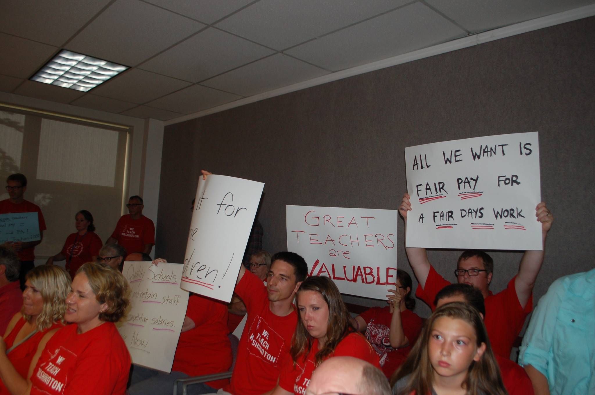 A group of supporters raise their signs advocating for fair teacher pay during the Sequim school board meeting on Tuesday, Sept. 5, at the Sequim High School auditorium as Sequim school district remains in mediation with the teachers’ union. Sequim Gazette photo by Erin Hawkins