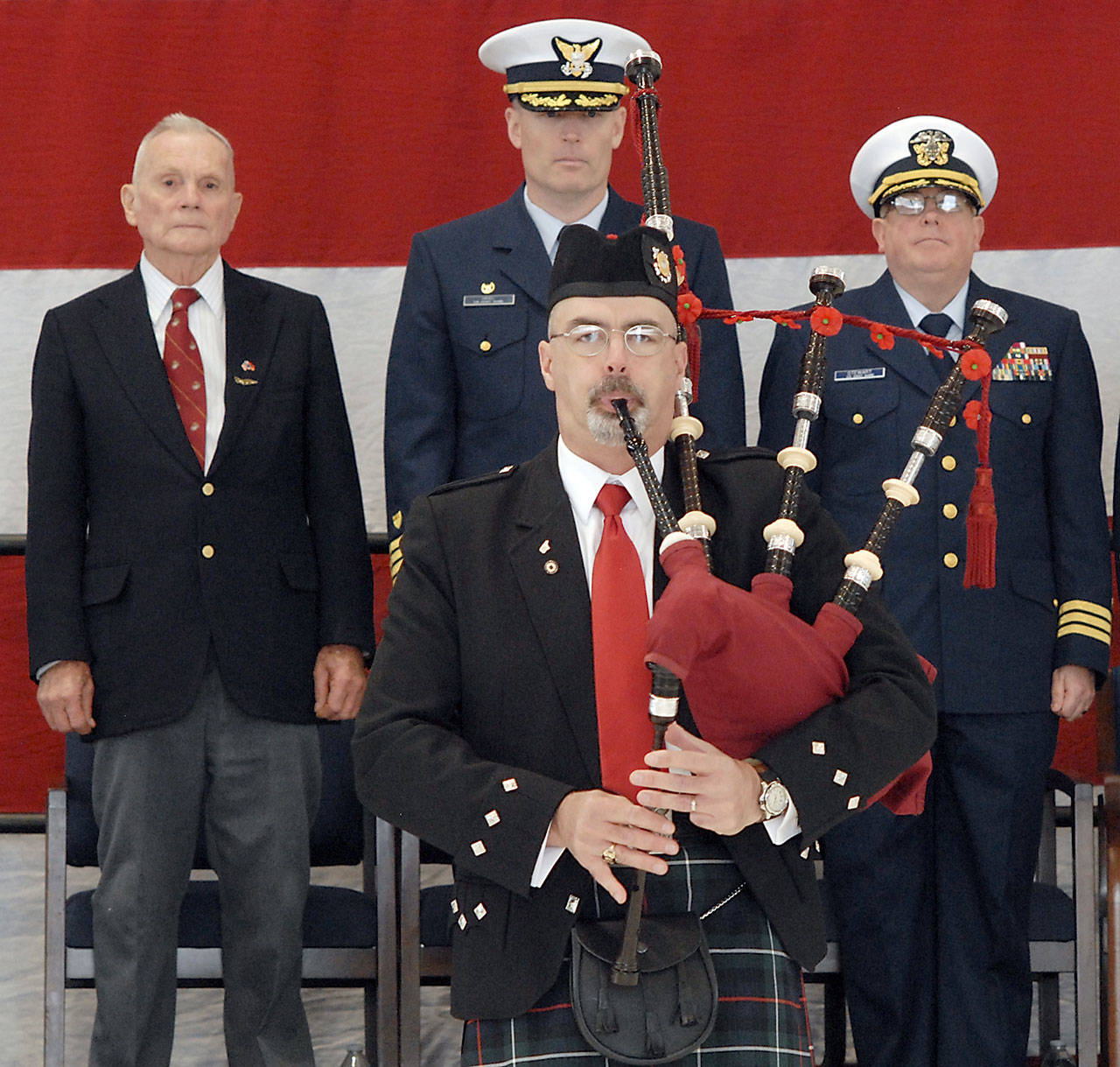 Bagpiper Rick McKenzie, a retiree from the U.S. Coast Guard, plays “Amazing Grace” to help close out Saturday’s Veterans Day ceremony. On the podium behind were, from left, retired U.S. Marine Corp Col. Thomas Johnson, Capt. Mark Hiigel, commanding officer of U.S. Coast Guard Air Station/Sector Field Office Port Angeles, and Coast Guard District 13 Chaplain Cmdr. William Stuart. (Keith Thorpe/Peninsula Daily News)